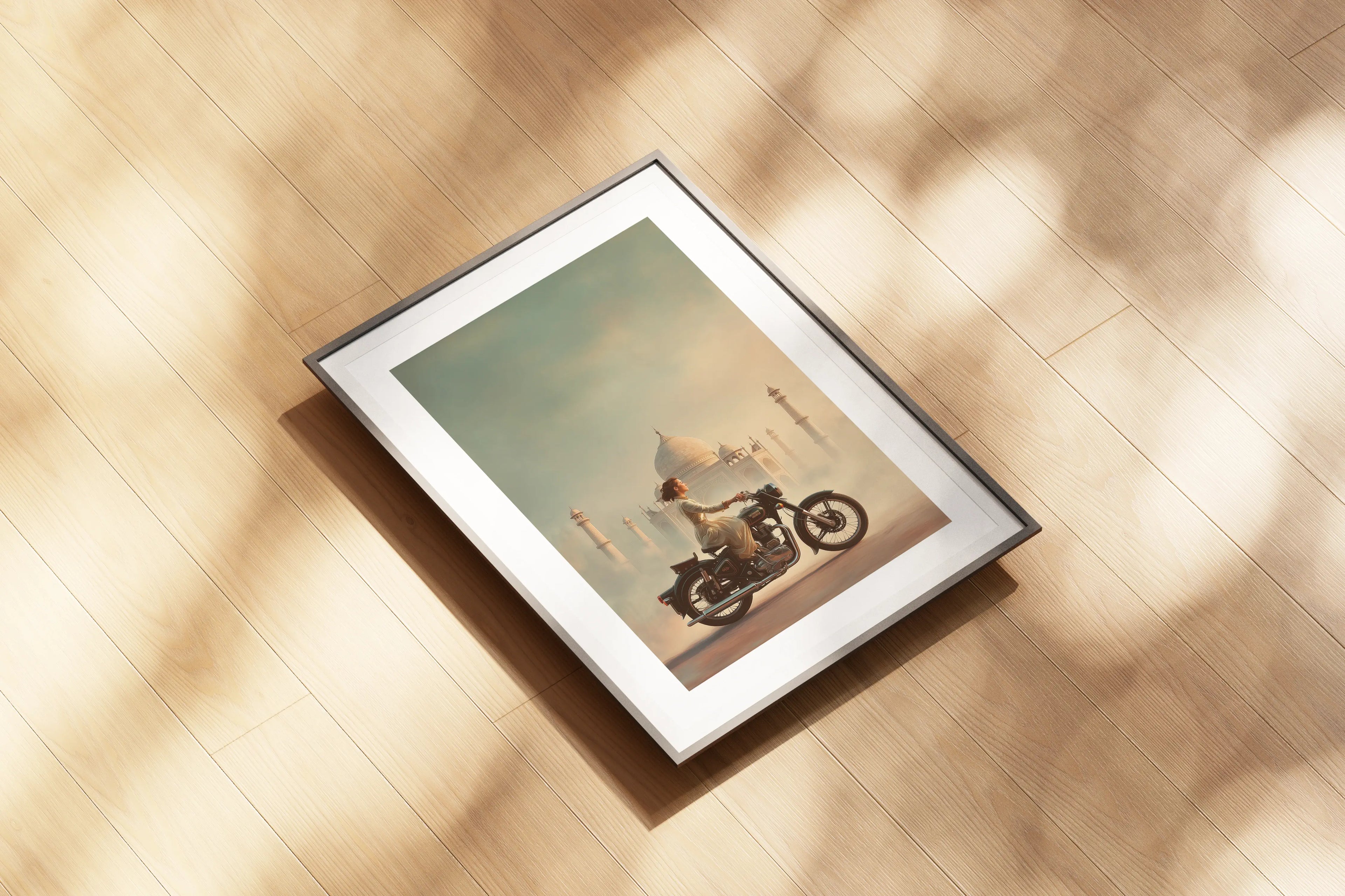 Affiche Royal Enfield aérographe posée au sol, motarde et Taj Mahal, reflets chrome et tons chauds.